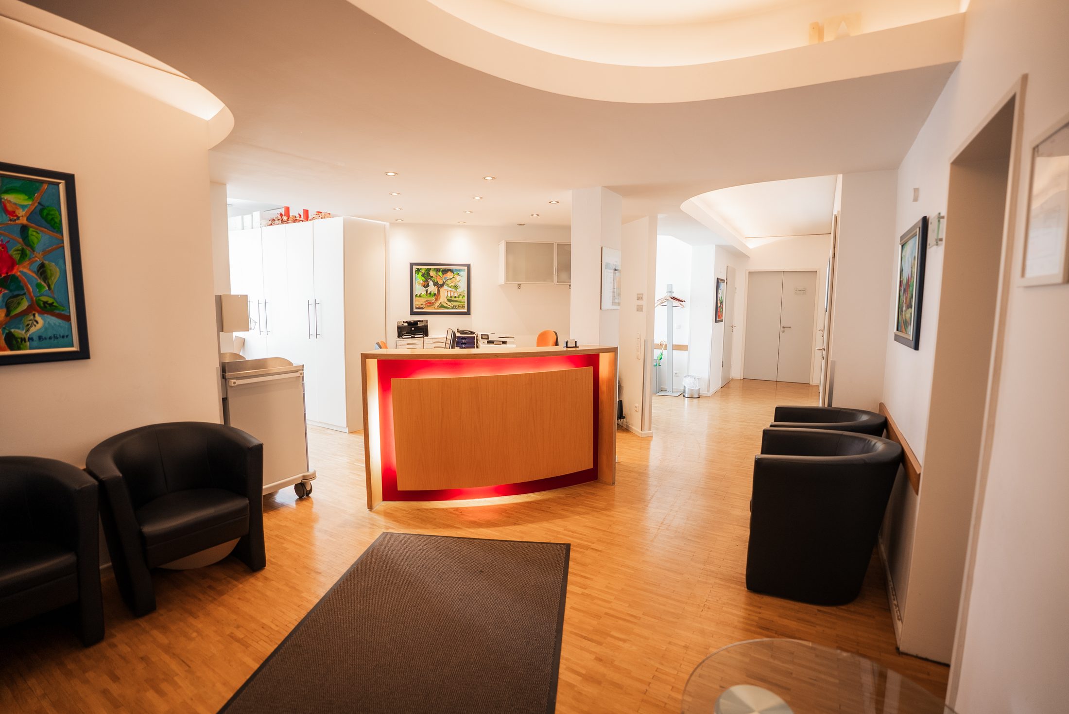 Wartebereich mit Polstersesseln und Bildern an der Wand