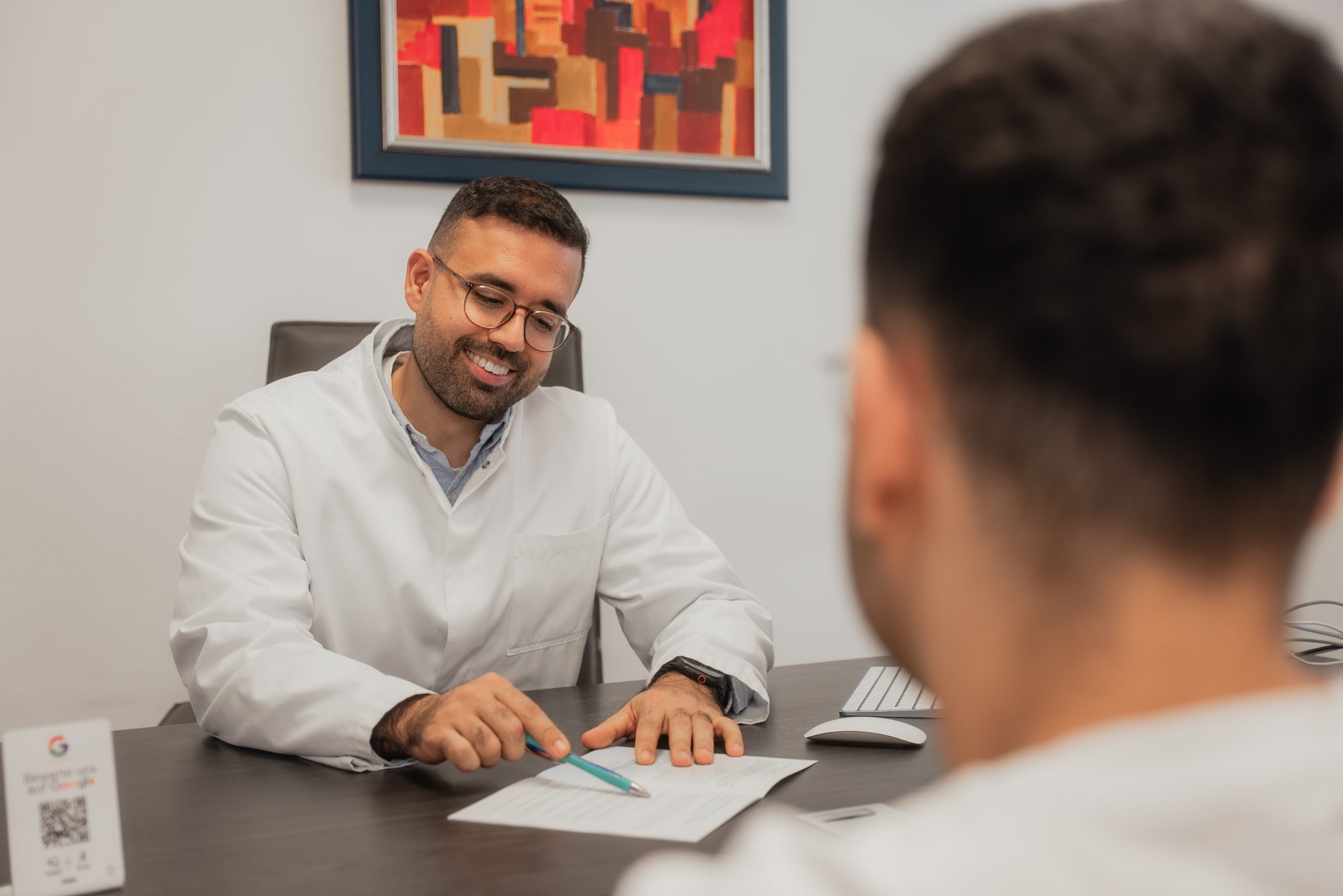 Dr. Afghanyar erläutert Informationsmaterial im Sprechzimmer